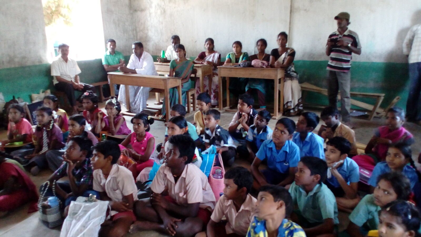 Children and volunteers seated together during an AWARD TRUST village education session