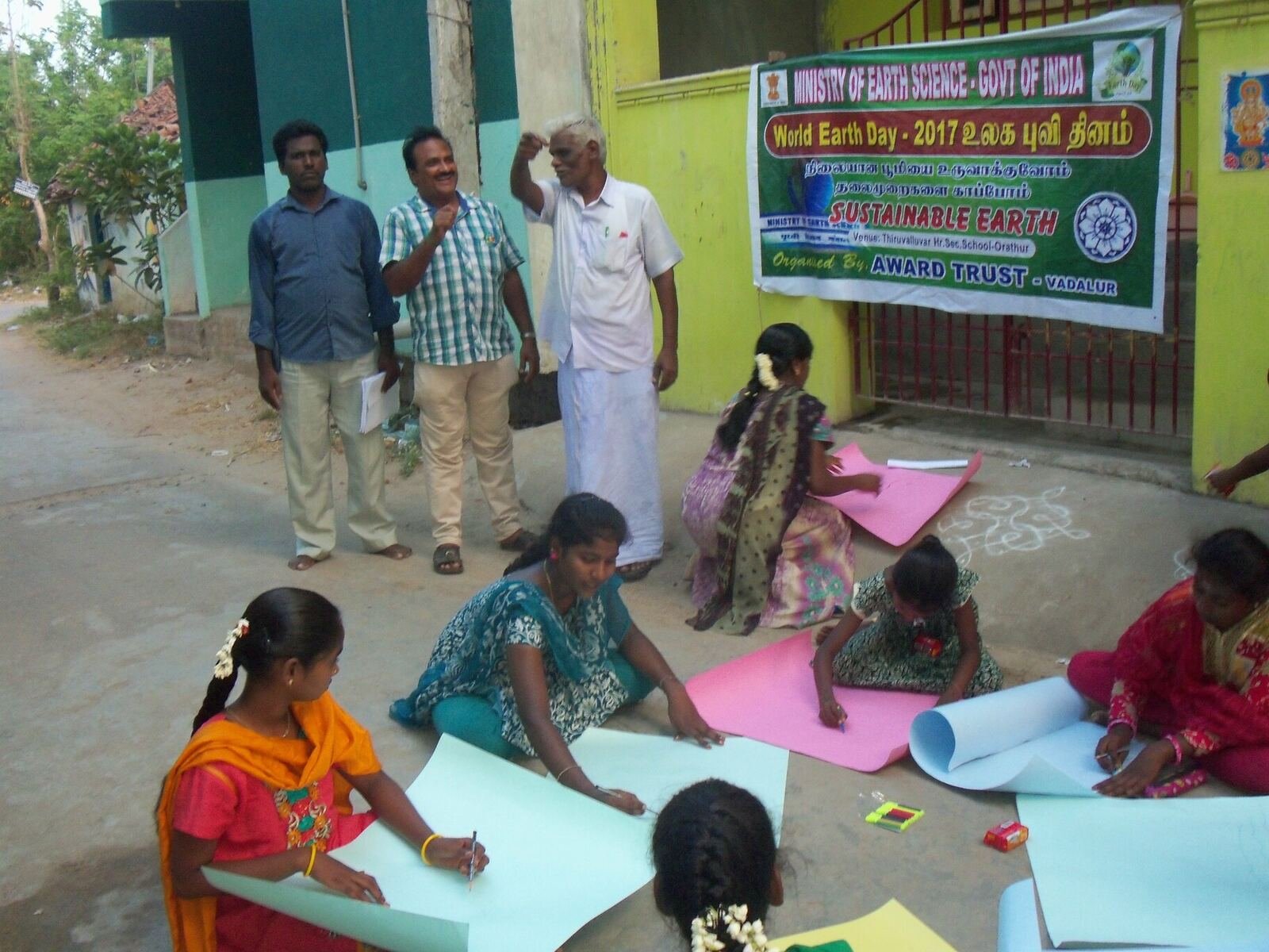 Girls drawing a kolam-style diagram during an AWARD TRUST World Earth Day awareness programme